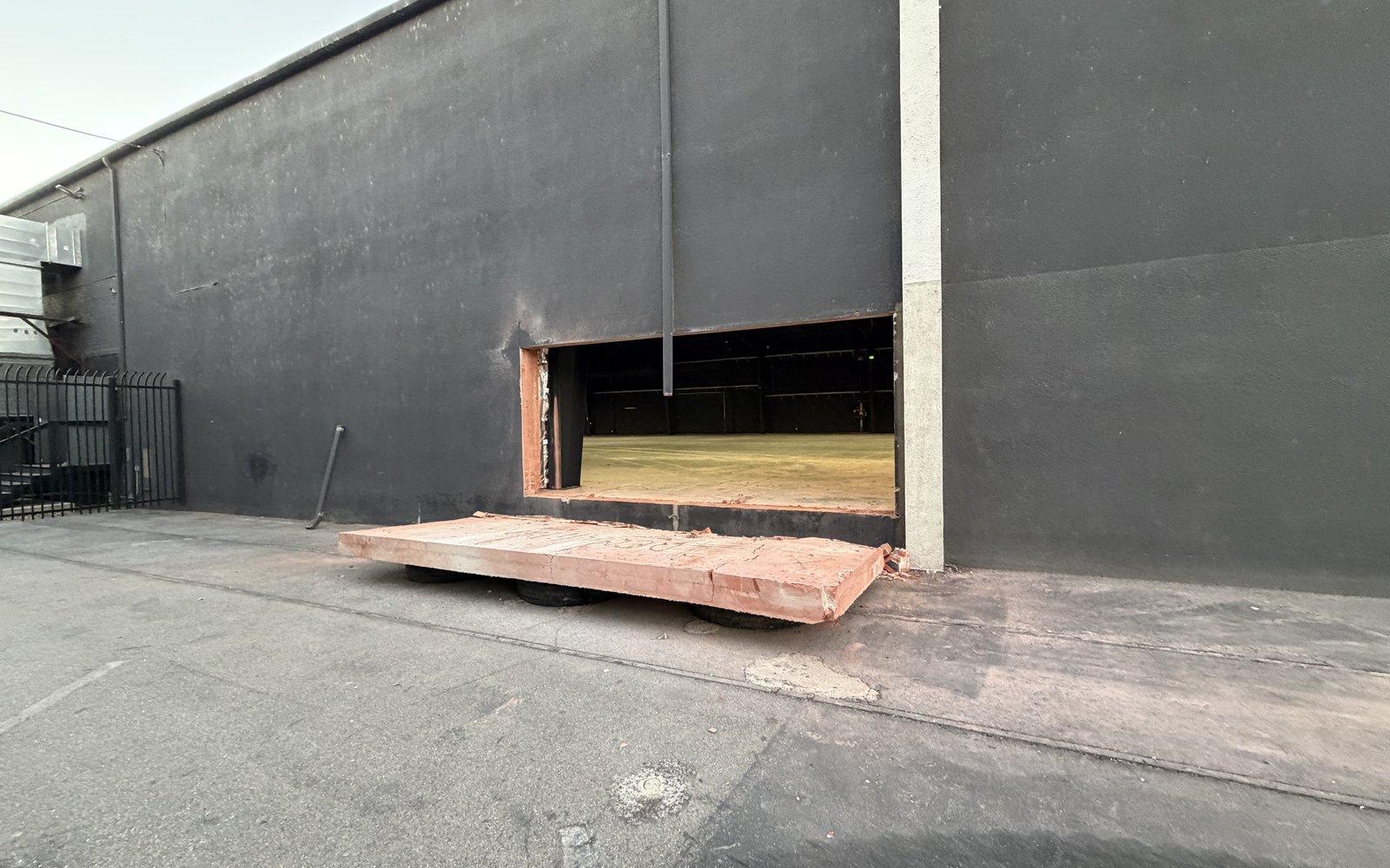 Finished opening cut through the warehouse wall with the removed concrete panel on a dolly out front