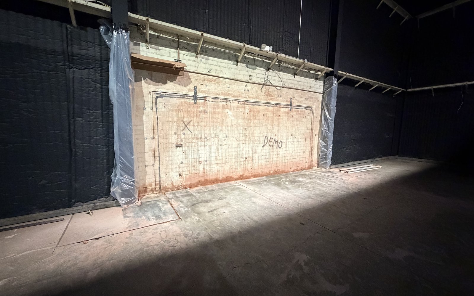 Interior warehouse wall marked out and prepped for cutting with plastic containment